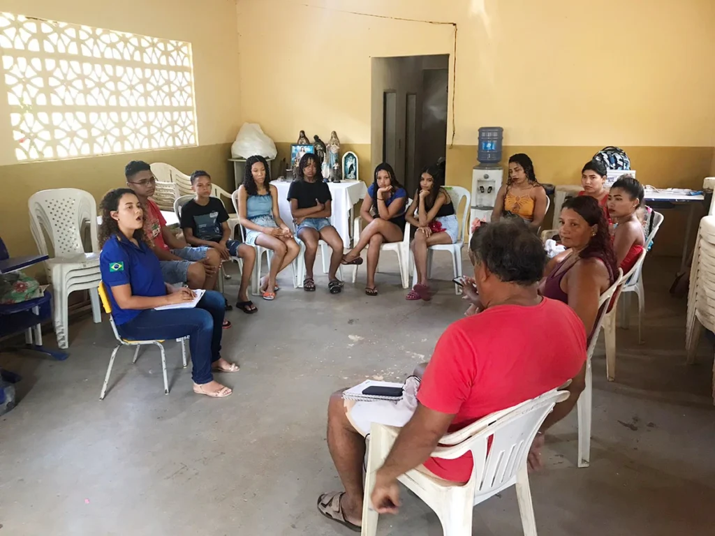 Jovens e adultos em roda de conversa sobre mudanças climáticas em espaço comunitário no Projeto Comunidades Pelo Clima da Plan Brasil.