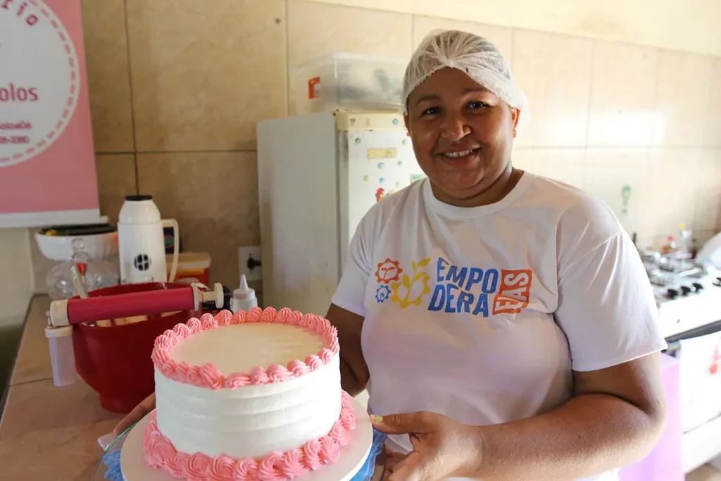 Mulher participante do Empodera Elas preparando bolo decorado como forma de geração de renda e empreendedorismo.
