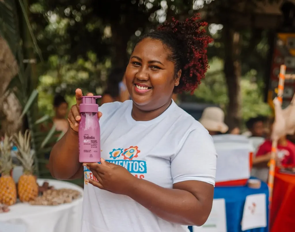 Jovem expositora apresentando produtos em feira do Empodera Elas, promovendo o empreendedorismo feminino e a valorização de saberes populares.