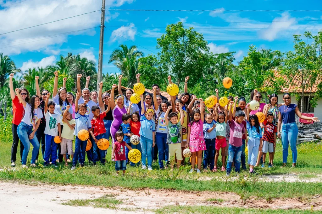 Crianças e adultos comemorando com balões coloridos durante evento do Projeto Ciranda em comunidade quilombola no Maranhão